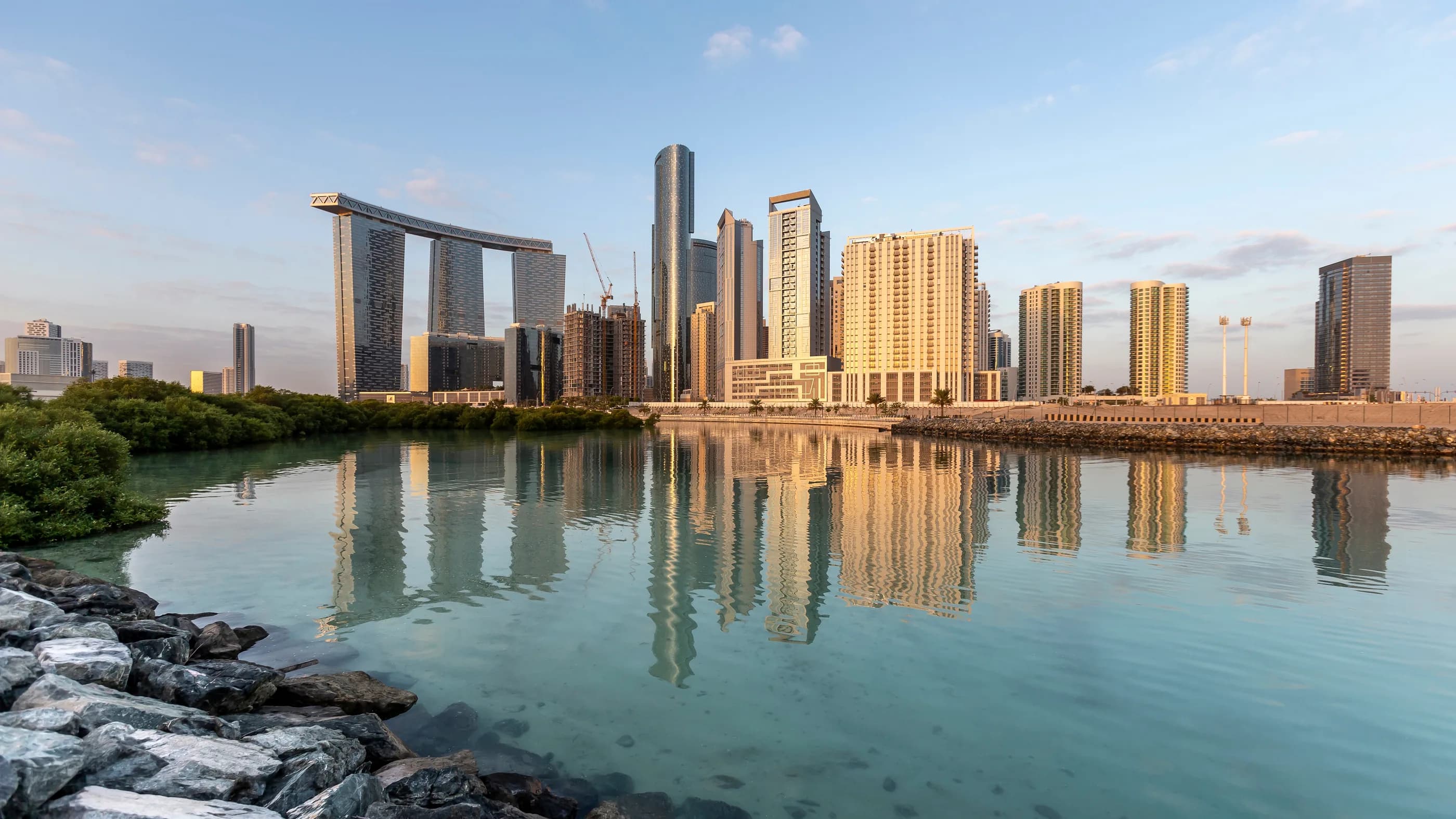Towers on Al Reem Island in Abu Dhabi reflected in a mangrove lagoon in the morning light.