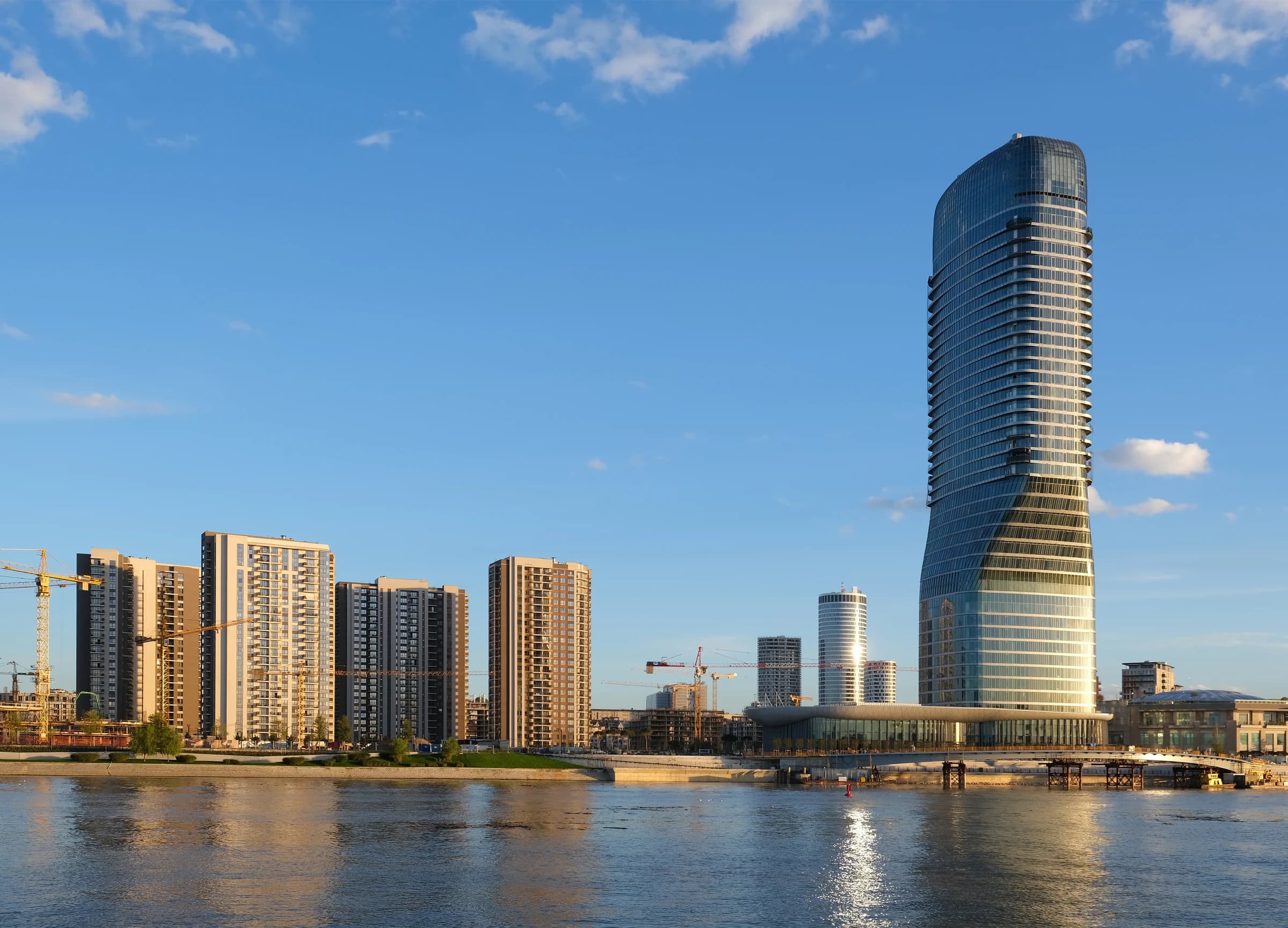 Belgrade Waterfront and Belgrade Tower beside the Sava River in warm sunlight.