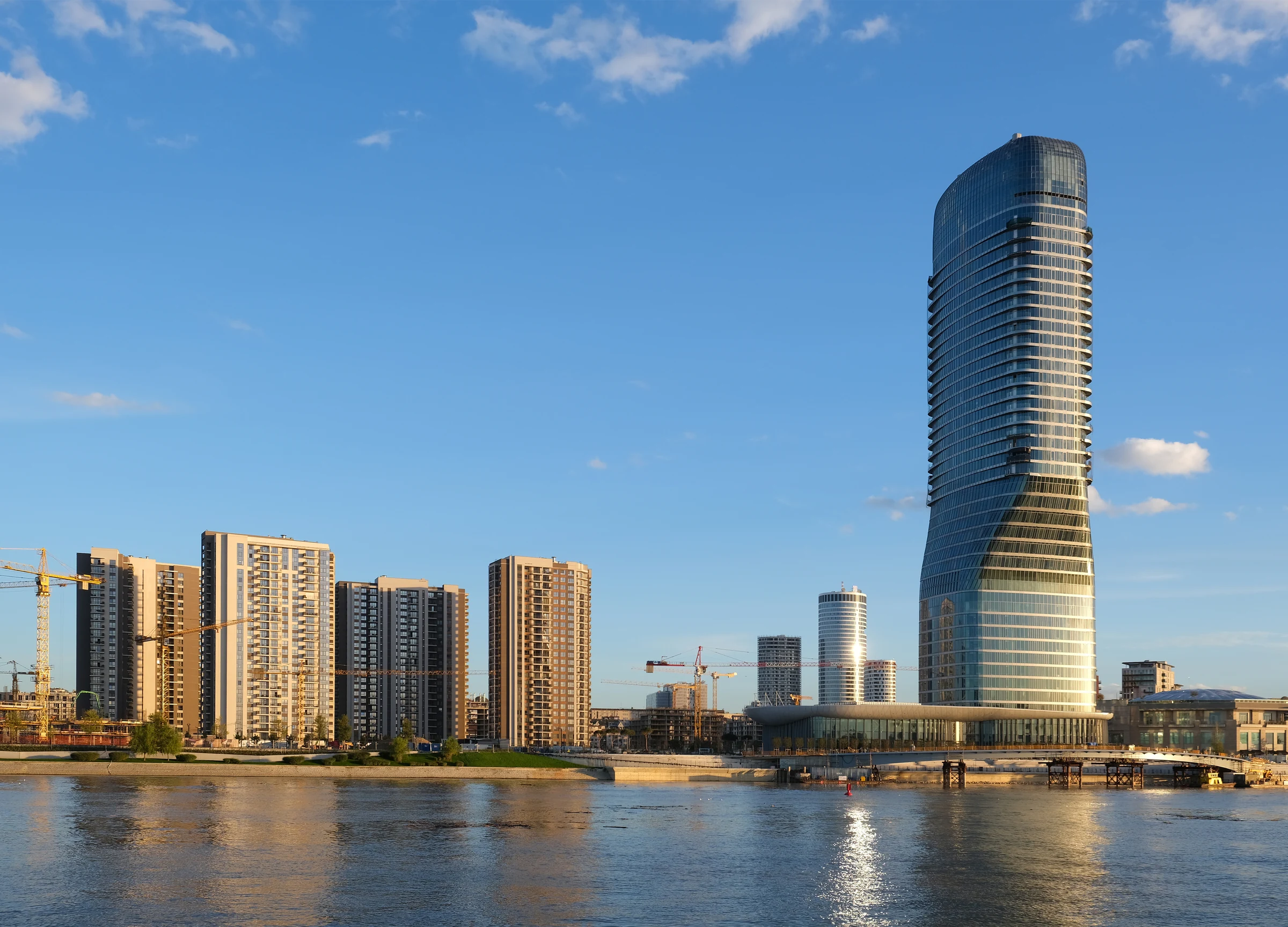 Belgrade Waterfront and Belgrade Tower beside the Sava River in warm sunlight.
